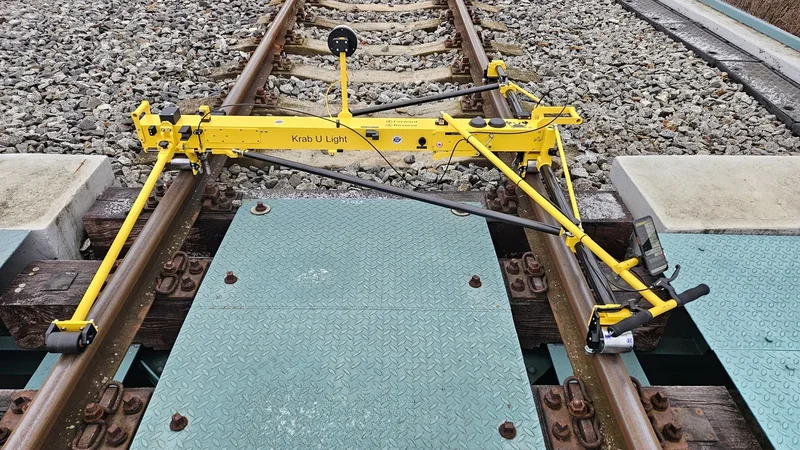 22 kg across the track: a measuring wheel on each rail, and a frame light enough for one person to lift off when a train approaches