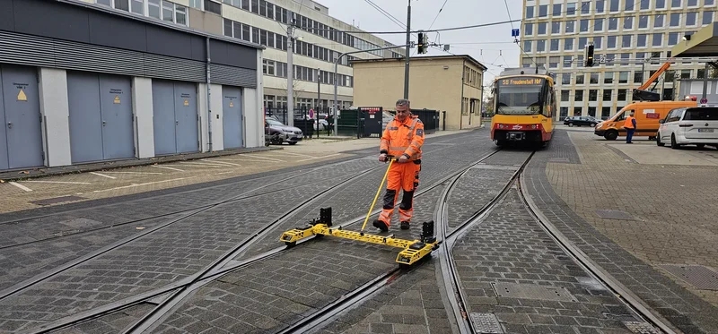 One operator measures a tram stop in normal traffic; VIPER is pulled on its tow bar and lifted off the track when a tram comes