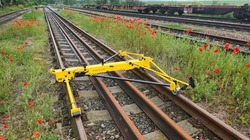 The frame is spread against both rails by spring force, which keeps the measuring wheels in contact through curves and switches